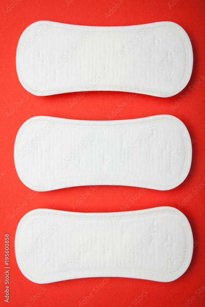 Obraz premium Three female pads on a red background, vertically.