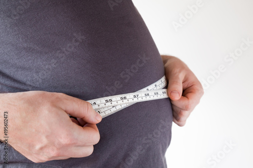 Fat overweight man measuring his waist. Plus size. New start for healthy lifestyle, body slimming, weight loss.. Cares about body.