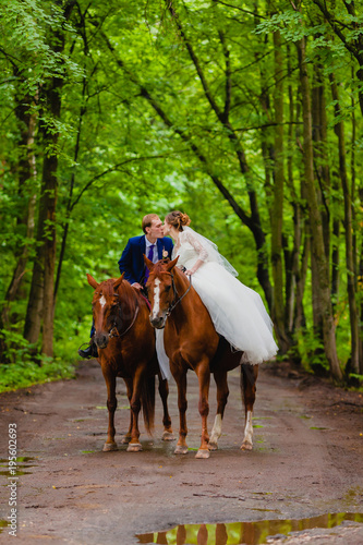 Beautiful newlyweds riding two horses