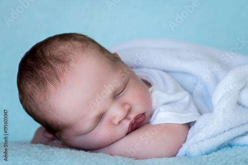 Newborn baby sleeping on his arms close up