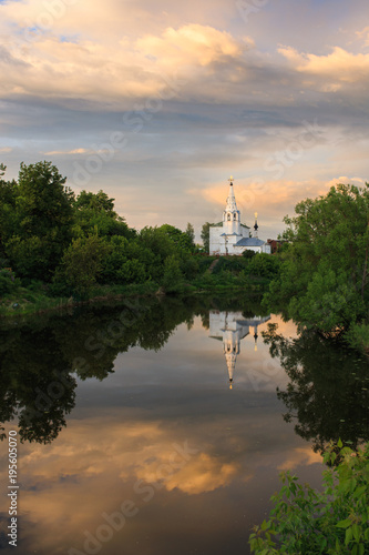 Church in Suzdal. In the foreground is the Kamenka river. Summer evening. Setting sun. A lot of green trees on the banks of the river. Beautiful landscape with an old temple by the river.