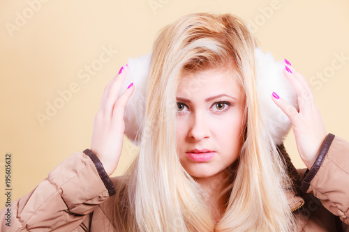 Blonde woman in winter earmuffs and jacket.