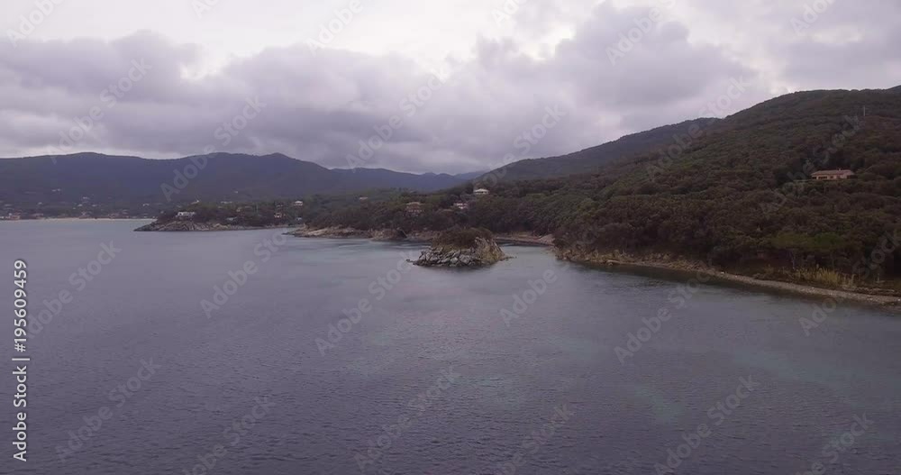 Aerial, beautiful calm sea and a tiny island near the island coast on cloudy day Aerial, beautiful calm sea and a tiny island near the island coast on cloudy day