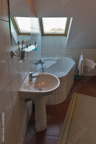 Modern bathroom with corner bath  washbasin and window.