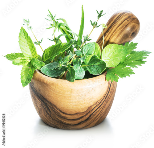 Different fresh green herbs in the wooden mortar. photo