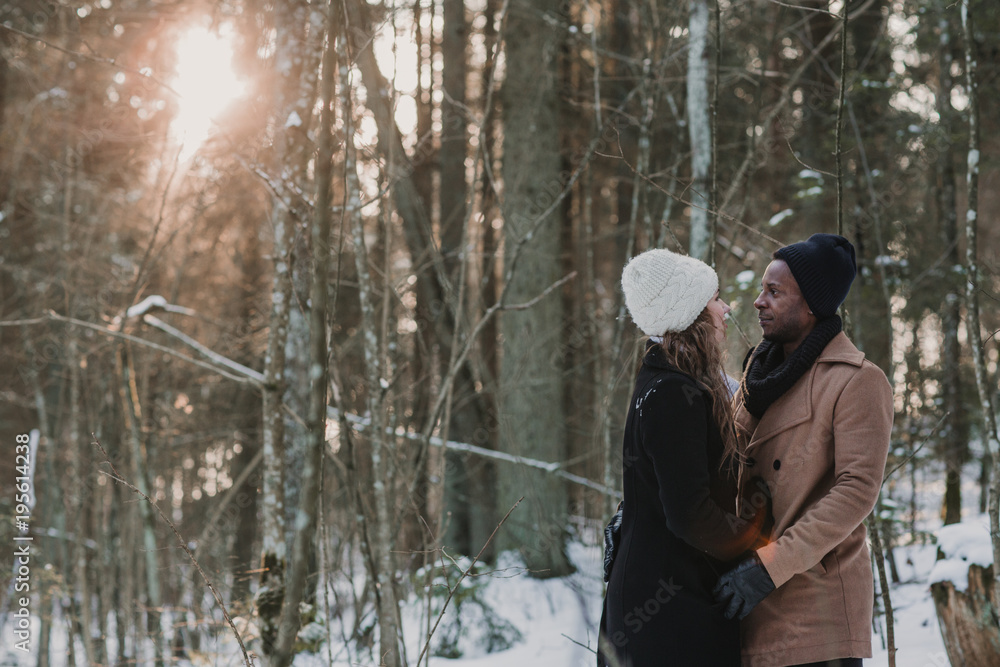 Multiracial couple bonding in winter forest Multiracial couple bonding in winter forest