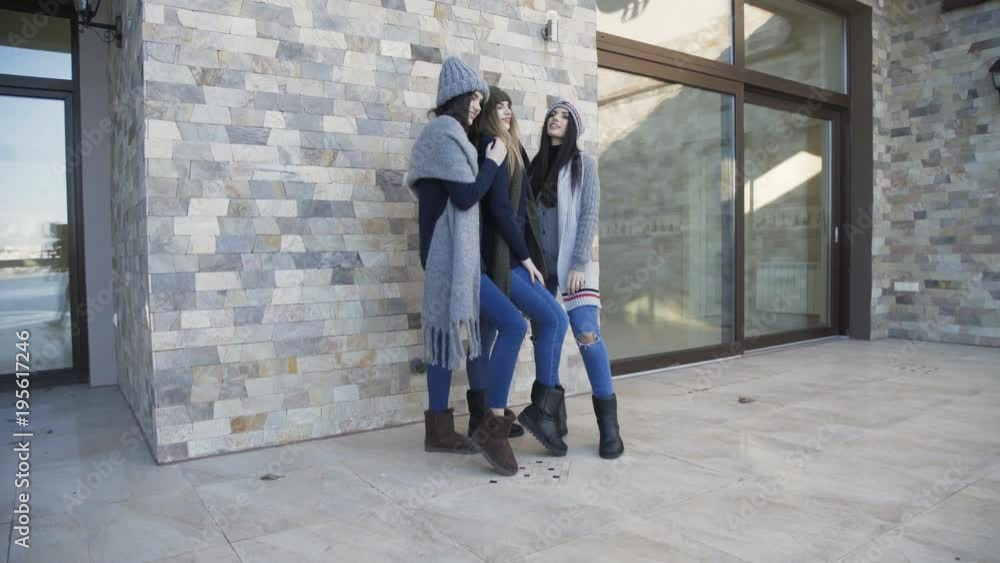 Three pretty girls in caps and scarf posing on the yard at house Three pretty girls in caps and scarf posing on the yard at house