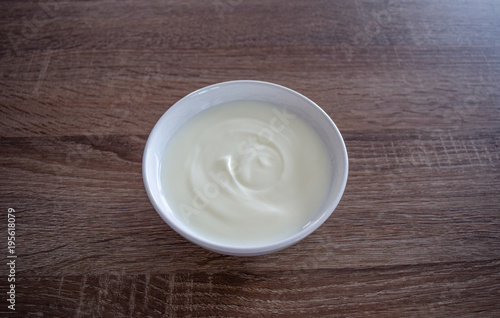 Ceramic bowl of white yogurt on wooden background from above view  plain yoghurt