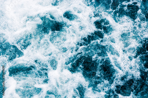 The blue surface of the water with white foam and gurgling, abstract marine background