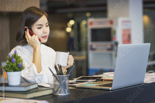 Wallpaper Mural Young Asian female entrepreneur talking on the phone while working at home office.	 Torontodigital.ca