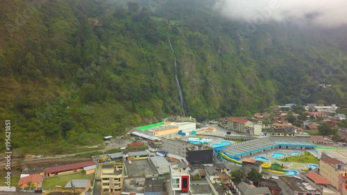 Experience the breathtaking beauty of Banos de Agua Santa in Ecuador with a mesmerizing aerial shot showcasing the hot springs and the majestic Virgins waterfall.
