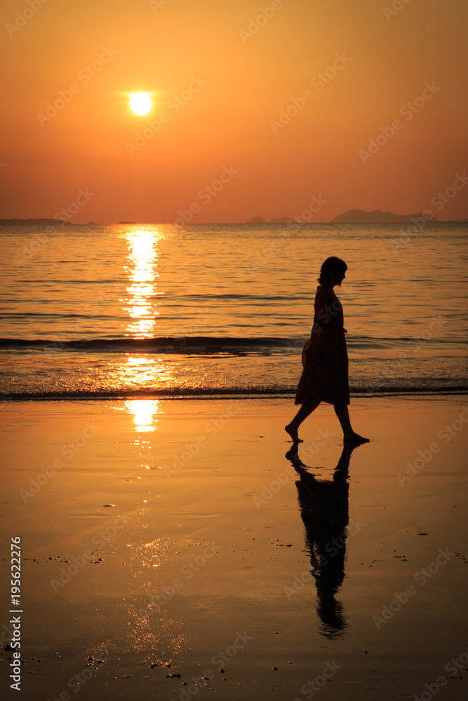 夕日の砂浜を歩く女の子