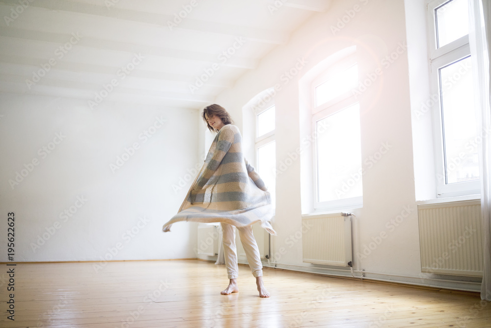 Happy mature woman standing in empty room in sunlight Happy mature woman standing in empty room in sunlight