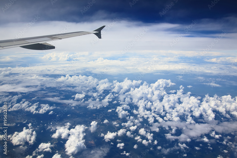 Fototapeta premium Beautiful clouds, land and wing of an airplan, view from the airplane window.