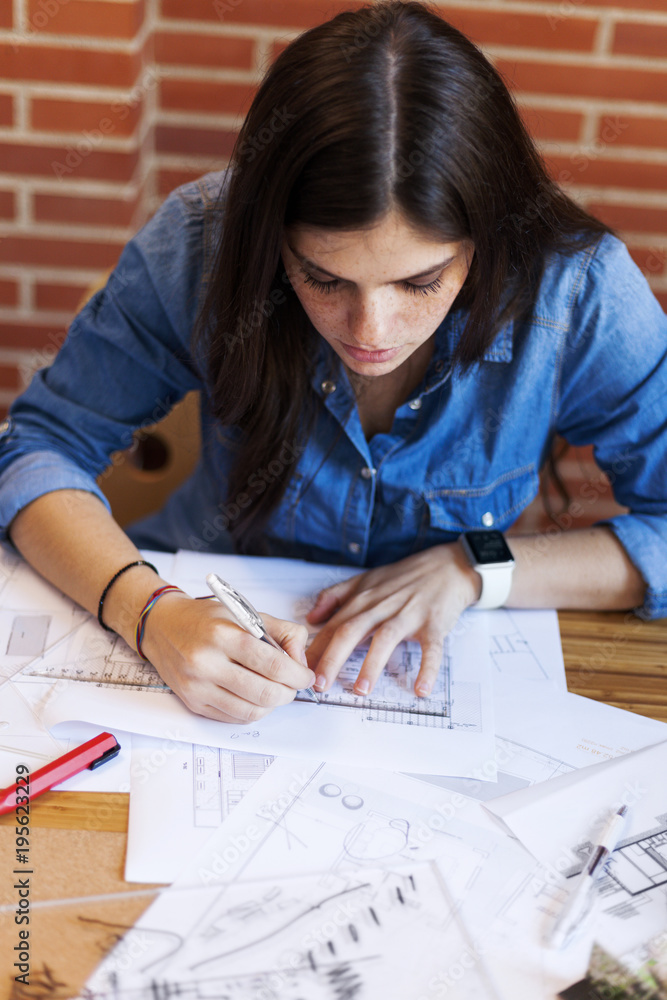 Young woman working in architecture office, drawing blueprints Young woman working in architecture office, drawing blueprints