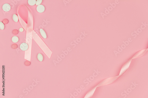 Pink tape as symbol of women illness mammary cancer with medicine pills drugs isolated on pink background