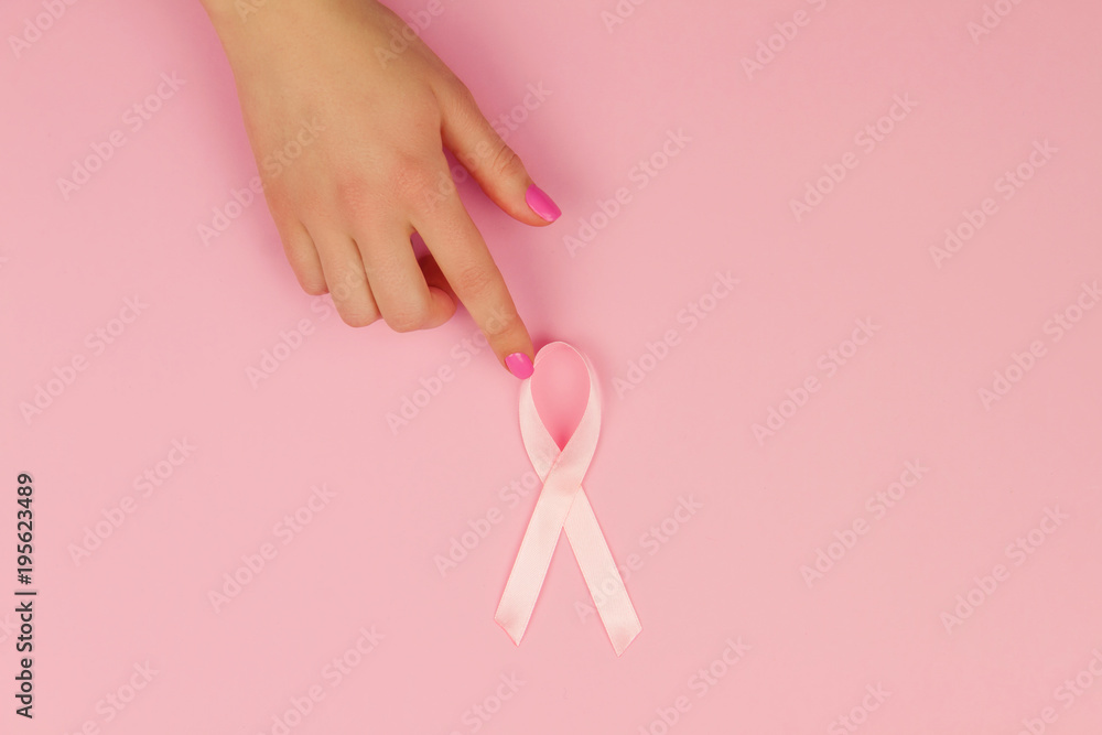 Woman's hand with pink tape as symbol of women illness mammary cancer isolated on pink background Woman's hand with pink tape as symbol of women illness mammary cancer isolated on pink background
