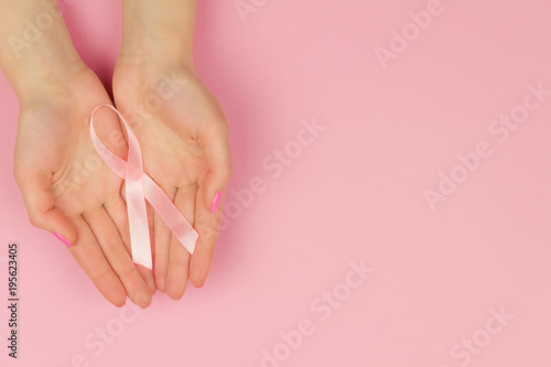 Woman hand with pink tape as symbol of women illness mammary cancer isolated on pink background photo