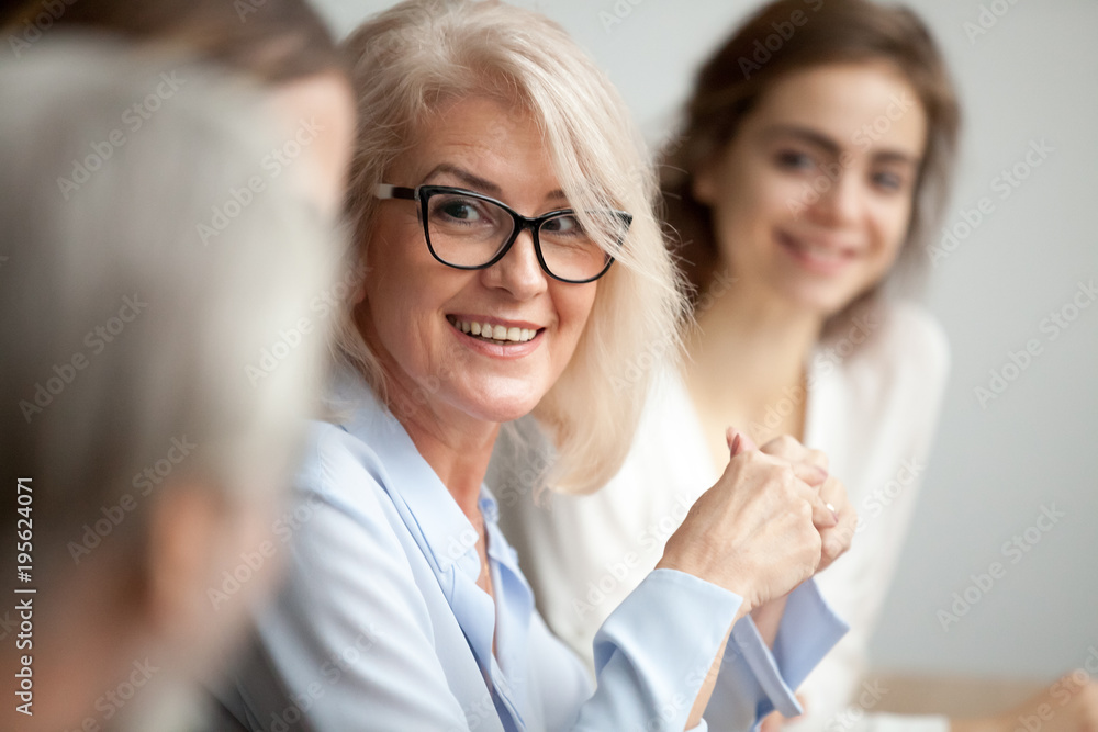 © fizkes - Smiling aged businesswoman in glasses looking at colleague at team meeting, happy attentive female team leader listening to new project idea, coach mentor teacher excited by interesting discussion © fizkes - Smiling aged businesswoman in glasses looking at colleague at team meeting, happy attentive female team leader listening to new project idea, coach mentor teacher excited by interesting discussion
