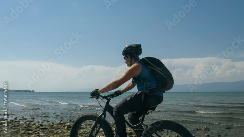 Fat bike also called fatbike or fat-tire bike in summer driving on the beach. The guy is going straight on the beach. On the sand on such a bike ride is not difficult.