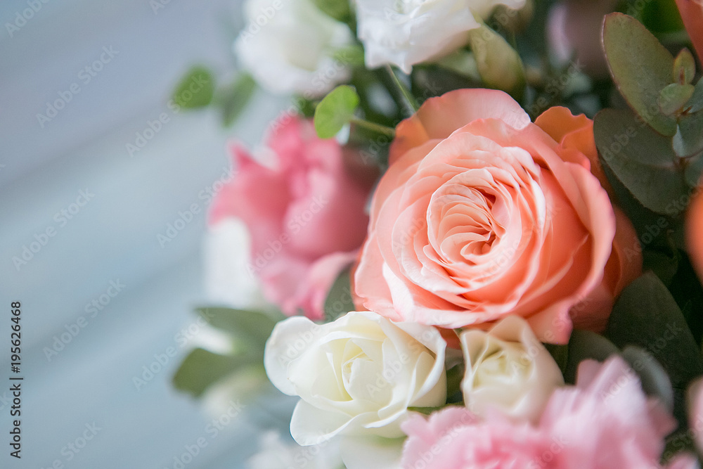 Delicate bouquet of roses, eustomams and carnations with eucalyptus branches on a light blue wooden background