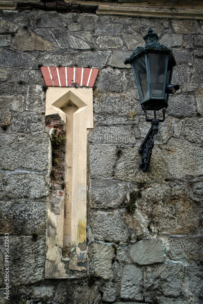 historic stone wall of the castle with a yellow niche and lamp historic stone wall of the castle with a yellow niche and lamp