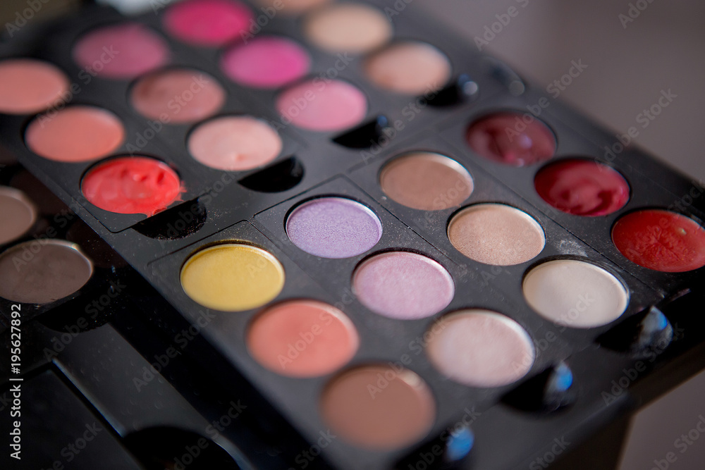 Multicolored eyeshadow and lipstick in a pallet close up Multicolored eyeshadow and lipstick in a pallet close up