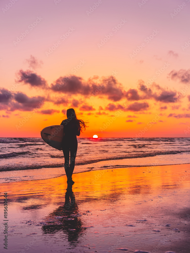 Silhouette of the surfer girl with surfboard on a beach at sunset. Surfer and ocean