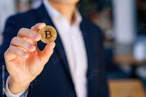 Cryptocurrency mining. Golden bitcoin coin. Businessman holding in hand symbol of cryptocurrency, electronic virtual money for web banking and international network payment, selective focus.