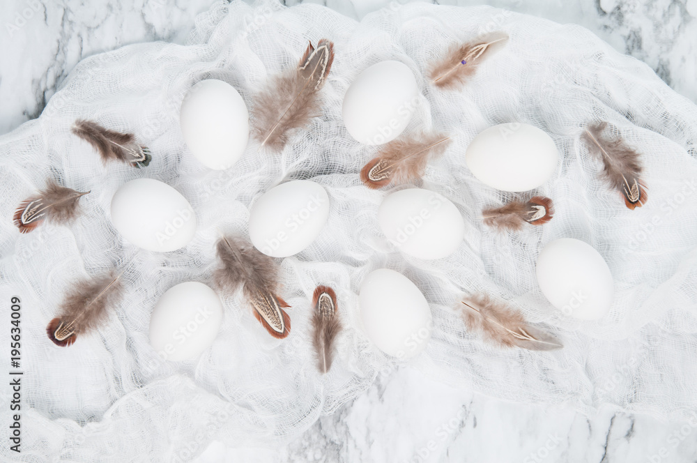 white eggs and brown feathers on a marble counter top white eggs and brown feathers on a marble counter top