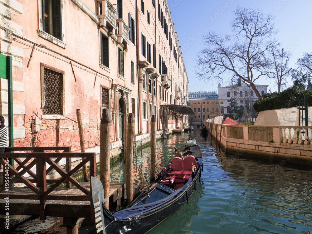 the gondola, a traditional Venetian boat, moored in a narrow canal bordering ancient palaces