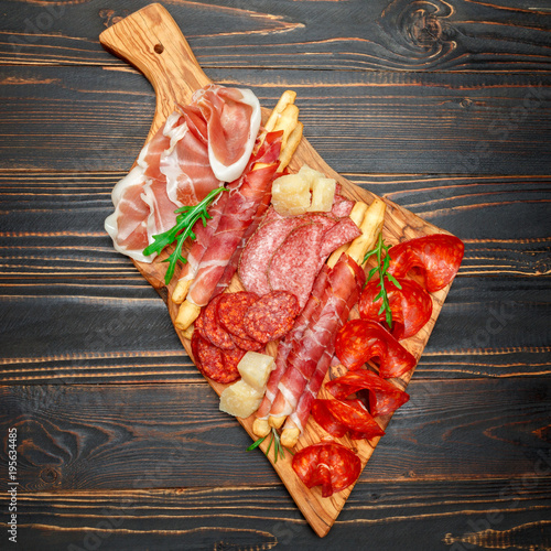 Cold smoked meat plate with pork chops, prosciutto, salami and bread sticks