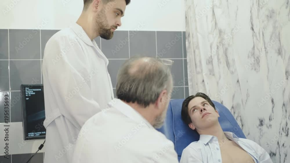 Two doctors conduct an examination with patient. 4K Two doctors conduct an examination with patient. 4K