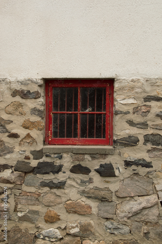Square red wooden window in a stone and whitewashed wall