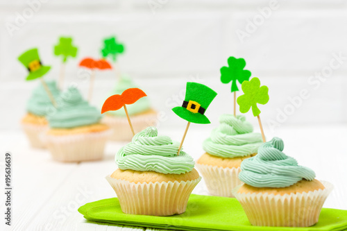 St. Patrick s Day theme colorful horizontal banner. Cupcakes decorated with green buttercream and craft felt decorations in form of leprechaun hat  mustache  shamrock leaves on white background