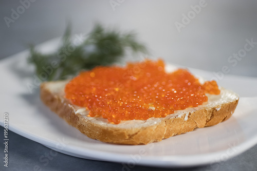Salmon caviar and  slice of toast bread on white plate.