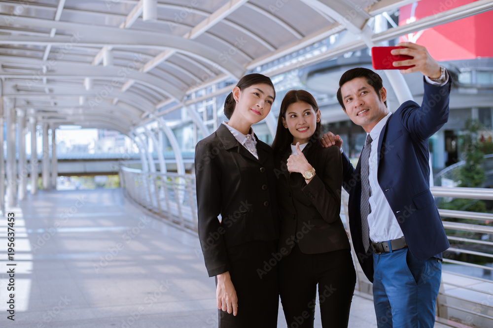 Asian businessman and business woman smile and taking a selfie by smartphone in the city Asian businessman and business woman smile and taking a selfie by smartphone in the city