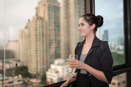 Happy Business woman have a drink in office after meeting standing by Panoramic windows with blur cityscape background. photo