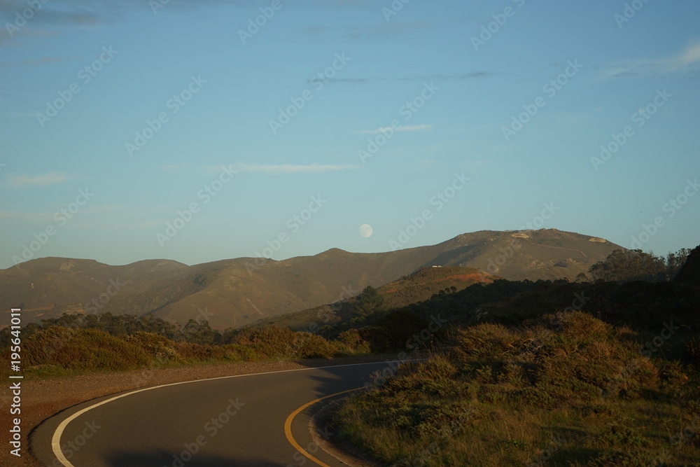 moon rise over california hills and winding road