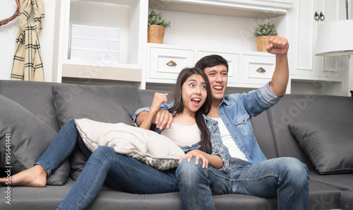 Excited Couple Watching FIFA World Cup Looking Front To Camera. Happy Man And Woman Supporting Favorite Football Team At Home. Fan Club Sports And Entertainment Concept
