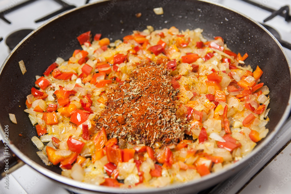 Pan with onion, pepper and seasoning on stove. Pan with onion, pepper and seasoning on stove.