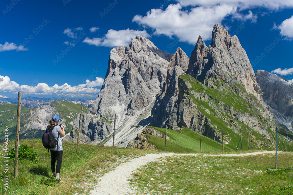 girl taking photos in beautiful summer landscape. Seceda Odle mountain in Italy Dolomites