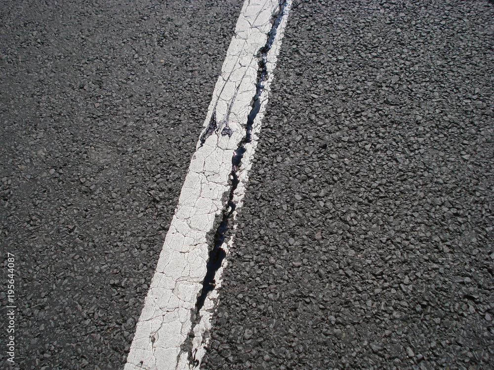White single dividing line over highway asphalt with a crack White single dividing line over highway asphalt with a crack