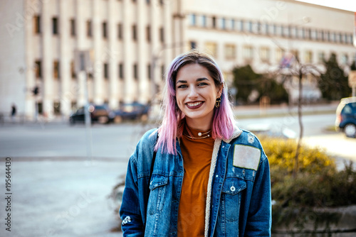 Picture of beautiful smiling rebellious woman with dyed hair at city street.