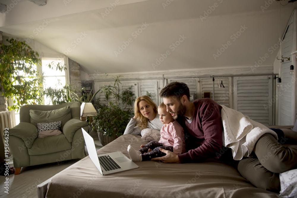 Happy family lies on bed and watching something on laptop Happy family lies on bed and watching something on laptop