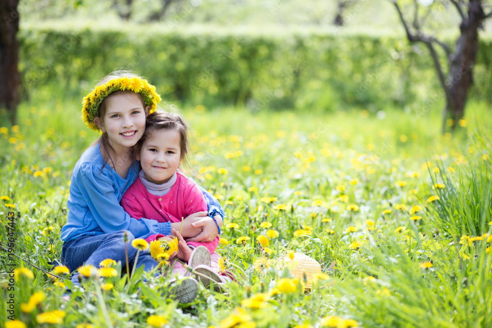 two cute baby playing on a spring meadow and looking at the camera