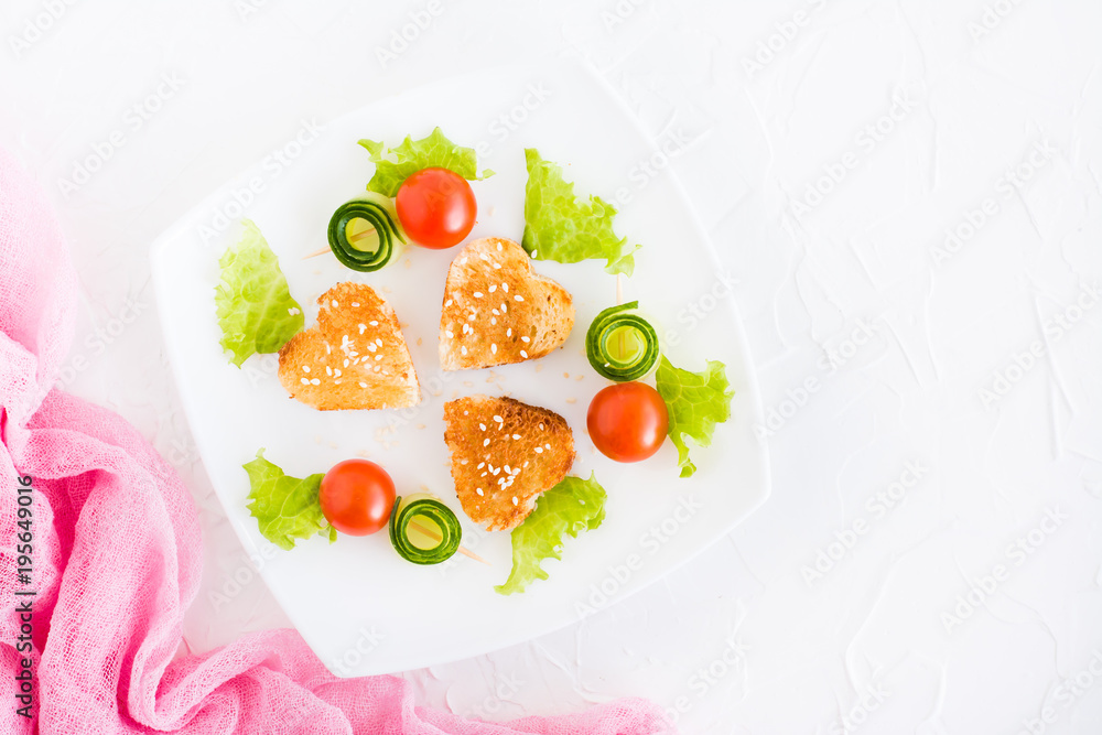 Toasts in the form of heart, cherry and cucumber on a plate. Dish served for lovers. Top view Toasts in the form of heart, cherry and cucumber on a plate. Dish served for lovers. Top view