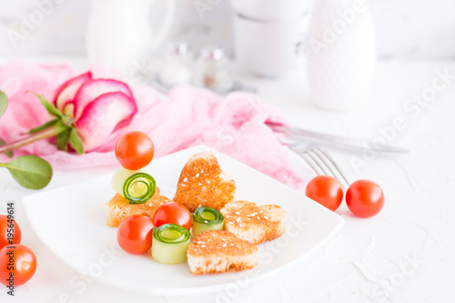 Toasts in the form of heart, cherry and cucumber on a plate. Dish served for lovers and rose.