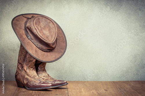 Tela Wild West retro leather cowboy hat and old boots front concrete wall background