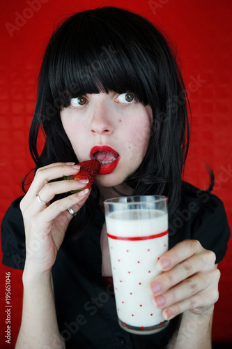 Mujer joven sosteniendo un vaso de leche con fresas  photo